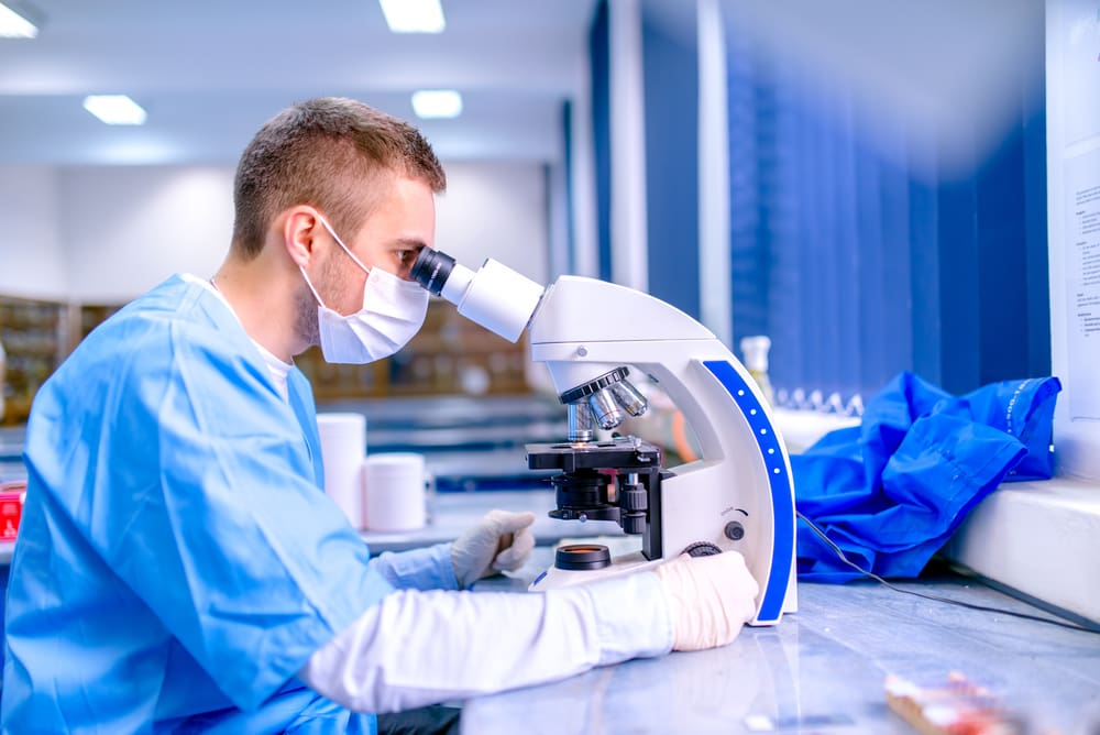 A scientist working in a chemistry laboratory, examining samples under a microscope.