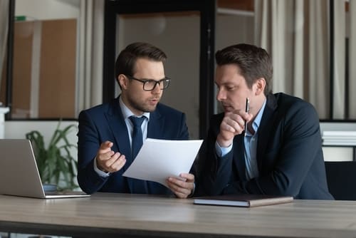 Two workers analyzing a document, possibly related to research and development (R&D).