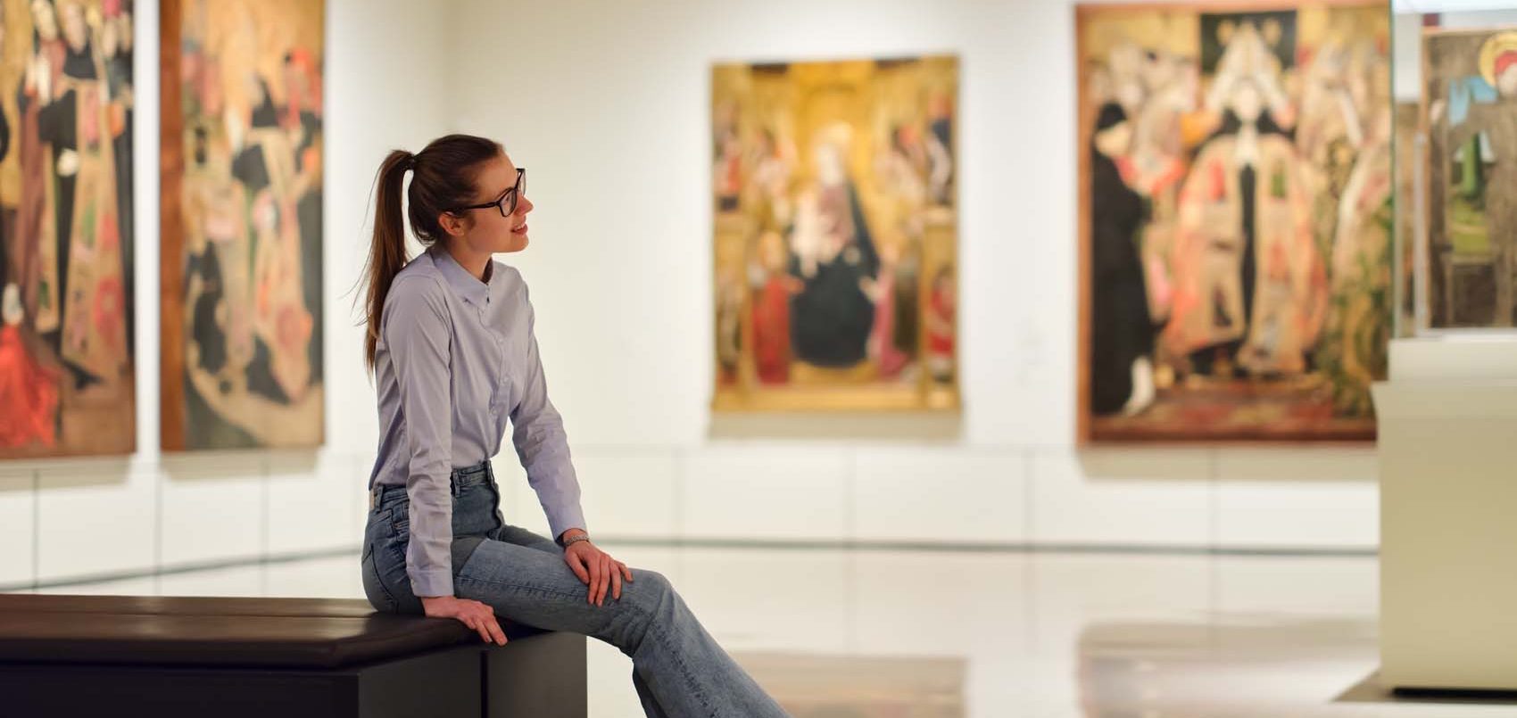 A woman sitting on a bench in a gallery.
